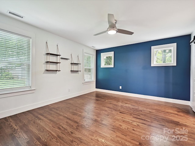 empty room with wood finished floors, ceiling fan, and baseboards