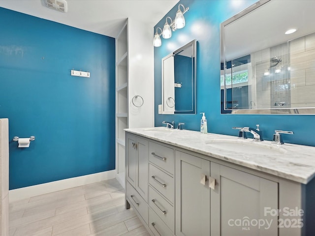 bathroom featuring tiled shower, built in features, baseboards, and double vanity