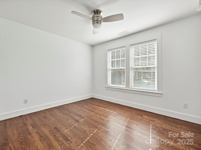 spare room featuring baseboards, ceiling fan, and dark wood-type flooring