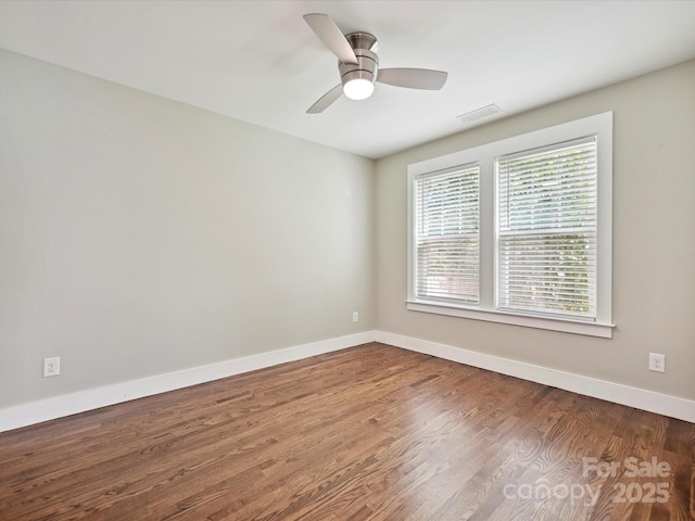 spare room with baseboards, wood finished floors, and a ceiling fan
