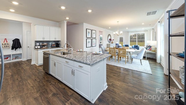 kitchen with light stone countertops, dishwasher, a sink, ornamental molding, and white cabinetry