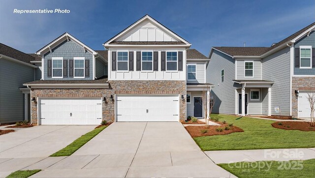 craftsman-style house with board and batten siding, driveway, an attached garage, stone siding, and a front lawn