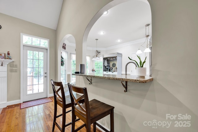 3610 Providence Mill Rd, Maiden, NC 28650 - kitchen featuring arched walkways, a breakfast bar area, light wood finished floors, light stone countertops, and hanging light fixtures