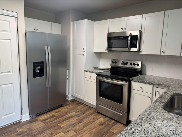 247 E Cabarrus Ave, Concord, NC 28025 - kitchen with stainless steel appliances, white cabinetry, light stone countertops, dark wood finished floors, and backsplash