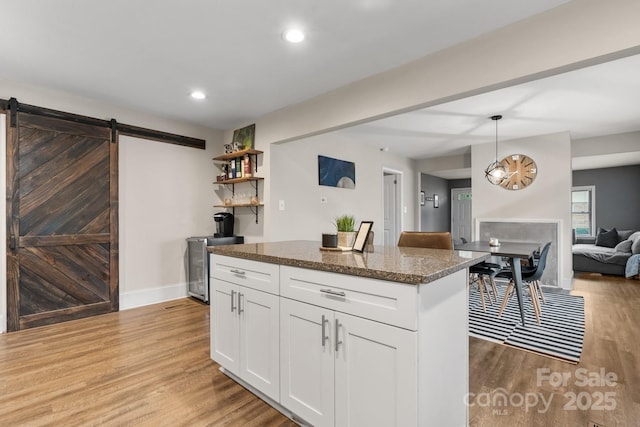 2212 Acme Rd, Belmont, NC 28012 - kitchen with a barn door, light wood-style floors, white cabinets, a kitchen island, and dark stone countertops