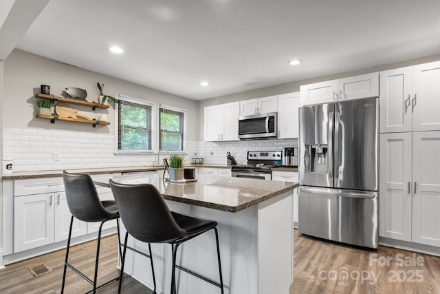 2212 Acme Rd, Belmont, NC 28012 - kitchen featuring stainless steel appliances, a breakfast bar, wood finished floors, dark stone counters, and a center island