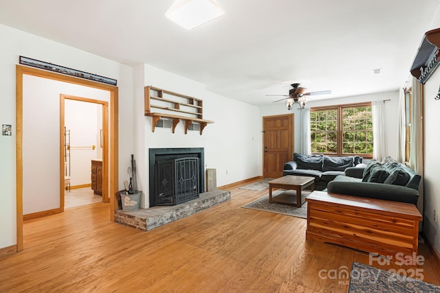 83 Snowy Cove Ln, Black Mountain, NC 28711 - living area featuring light wood finished floors, a fireplace with raised hearth, a ceiling fan, and baseboards