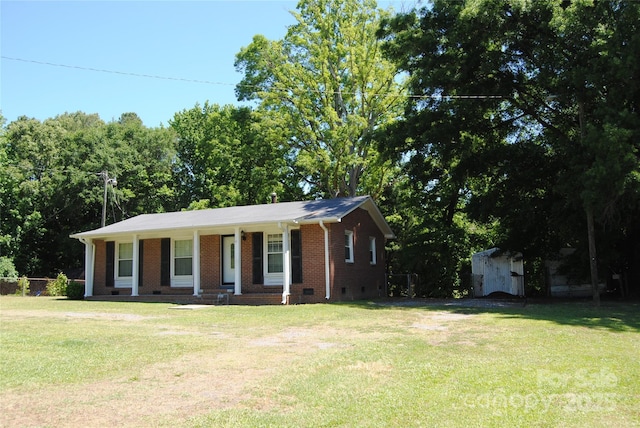 view of front facade featuring an outdoor structure, a front yard, a shed, a porch, and brick siding