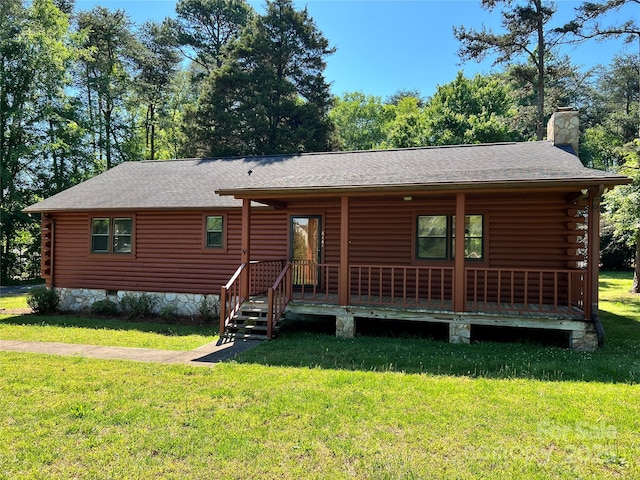log-style house with log exterior, a chimney, covered porch, and a front yard