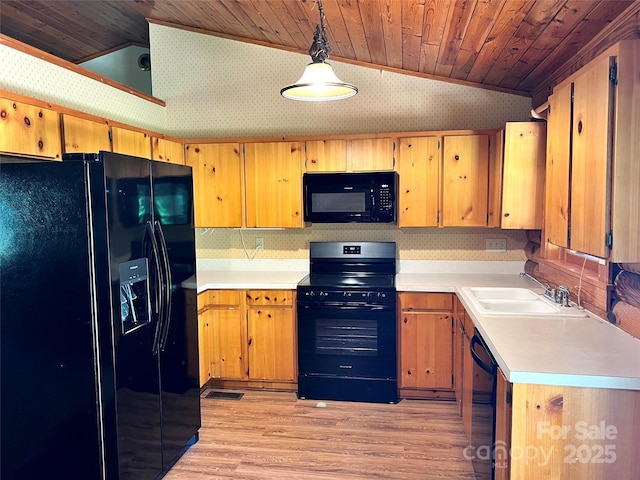 kitchen with black appliances, a sink, lofted ceiling, wallpapered walls, and light wood finished floors