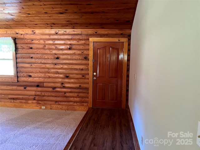 doorway with rustic walls, wood ceiling, dark wood-type flooring, and baseboards