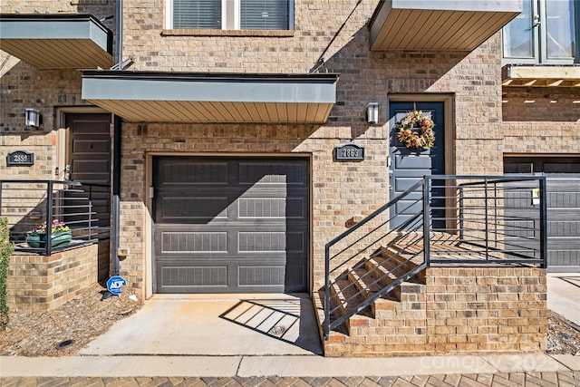 doorway to property featuring a garage and brick siding