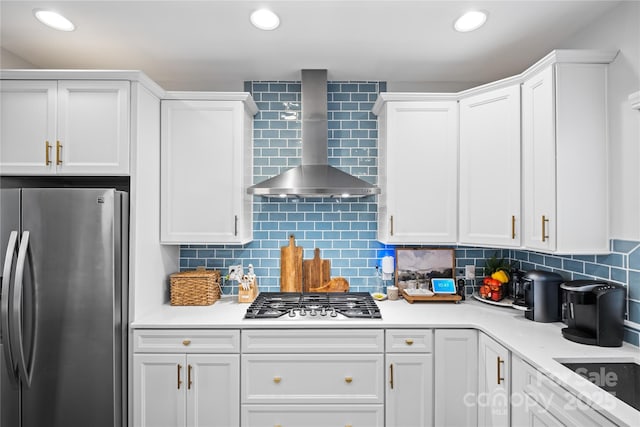 kitchen with stainless steel appliances, wall chimney range hood, light countertops, white cabinets, and recessed lighting