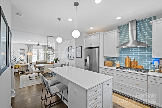 kitchen featuring stainless steel appliances, wall chimney range hood, light countertops, dark wood-type flooring, and recessed lighting