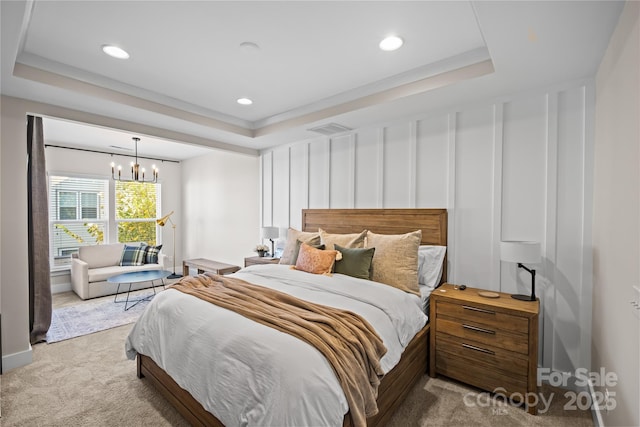 carpeted bedroom with a tray ceiling, a chandelier, and recessed lighting