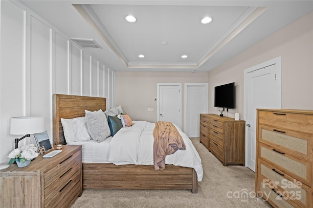 bedroom featuring a tray ceiling, light colored carpet, recessed lighting, and ornamental molding