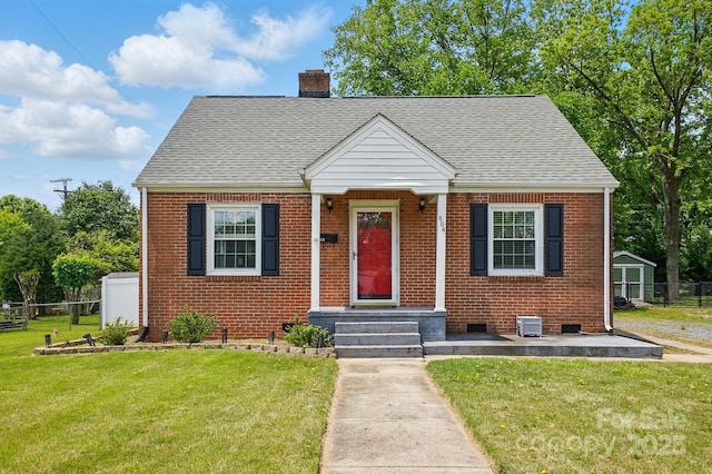 view of front of home featuring roof with shingles, a chimney, brick siding, and a front yard