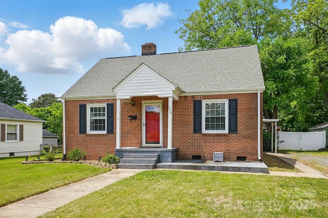 view of front of property with a chimney, a front yard, brick siding, and fence