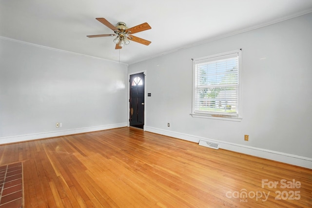 spare room with ceiling fan, crown molding, baseboards, and visible vents
