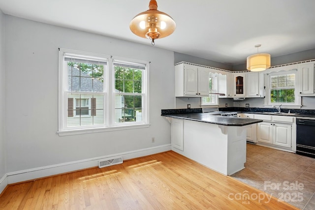 kitchen with a healthy amount of sunlight, black dishwasher, a sink, and visible vents