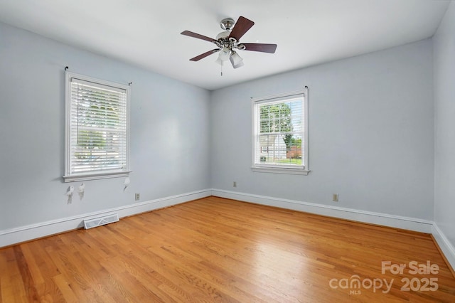 spare room featuring baseboards, a ceiling fan, visible vents, and wood finished floors