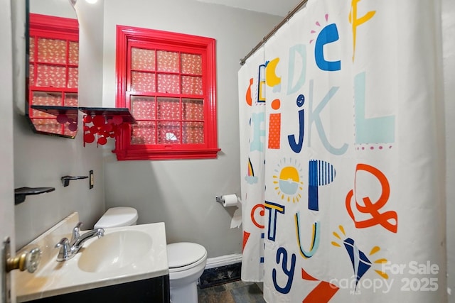 bathroom featuring toilet, a shower with curtain, stone finish floor, baseboards, and vanity