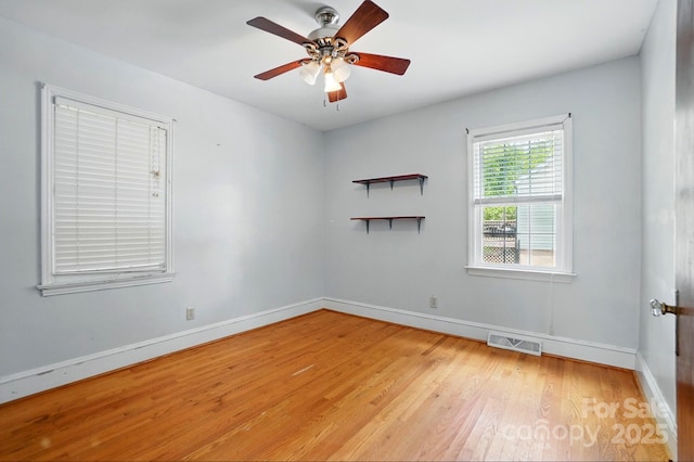 unfurnished room with a ceiling fan, visible vents, light wood-style flooring, and baseboards