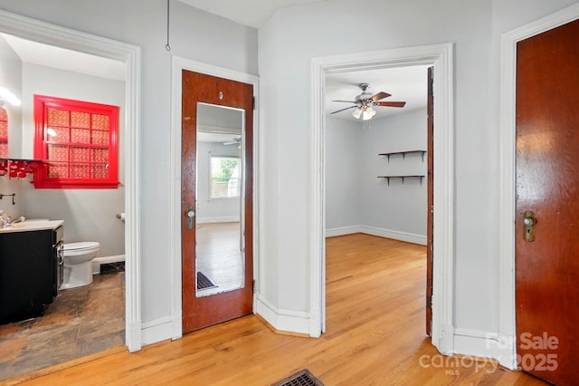 hallway with wood finished floors, baseboards, and a sink