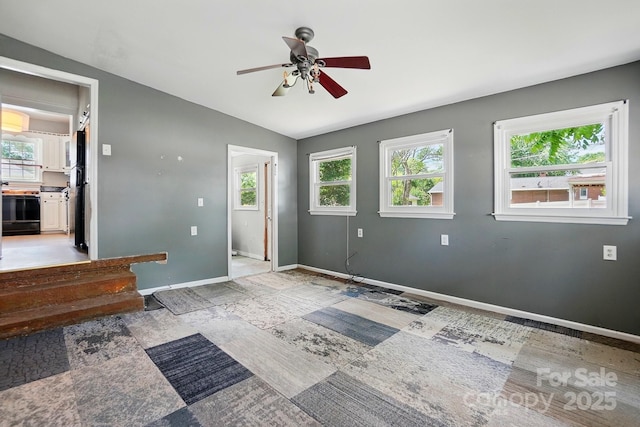 interior space with vaulted ceiling, baseboards, and ceiling fan