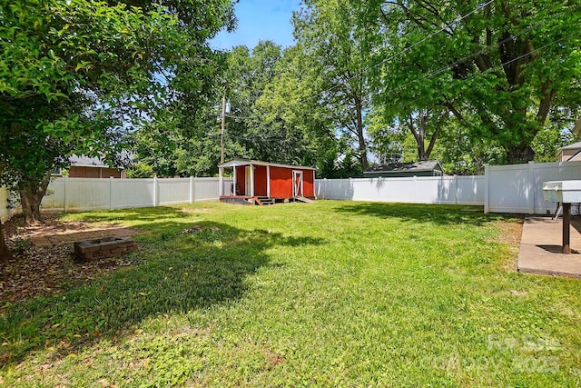 view of yard featuring an outbuilding, a fenced backyard, and a shed