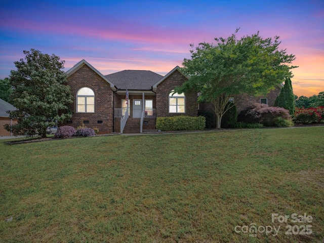 view of front of property with a front yard, a porch, and brick siding