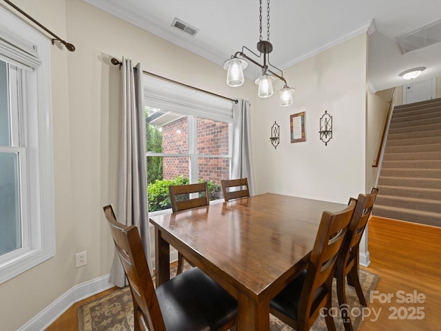 dining area featuring stairway, visible vents, crown molding, and wood finished floors