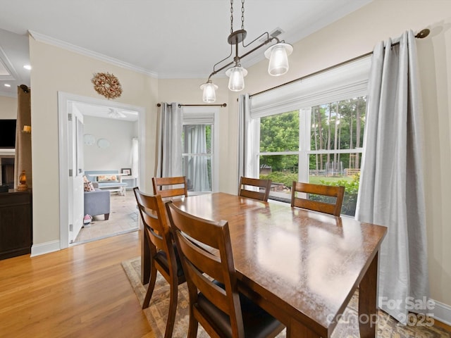 dining space with baseboards, ornamental molding, and light wood-style flooring