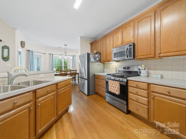 kitchen featuring a sink, appliances with stainless steel finishes, backsplash, light countertops, and light wood-style floors