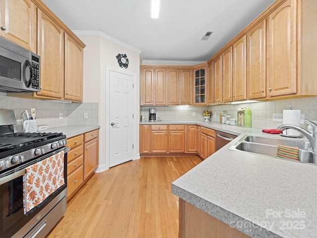 kitchen featuring appliances with stainless steel finishes, visible vents, a sink, decorative backsplash, and light wood-type flooring