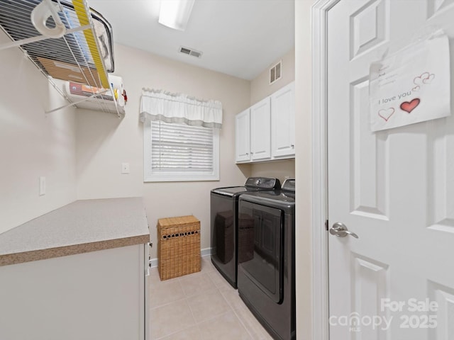 laundry room with baseboards, light tile patterned floors, visible vents, washing machine and clothes dryer, and cabinet space