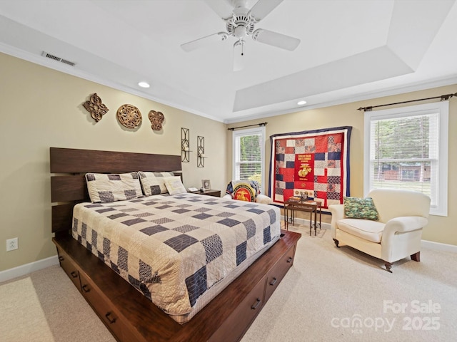 carpeted bedroom with a tray ceiling, crown molding, visible vents, and multiple windows