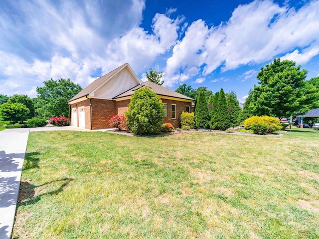 view of front of house featuring an attached garage, brick siding, driveway, and a front lawn
