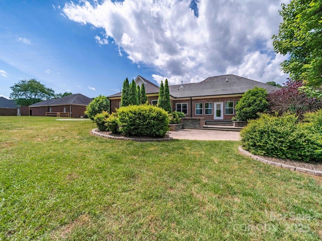 rear view of property featuring a patio, brick siding, and a lawn