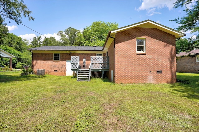 back of property featuring crawl space, brick siding, a deck, and a yard
