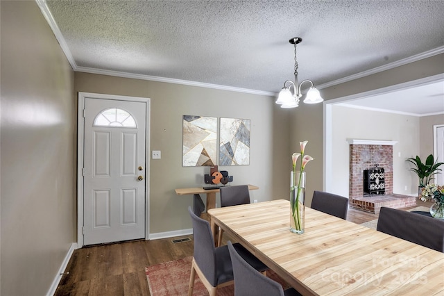 dining room featuring dark wood-type flooring, a textured ceiling, a chandelier, ornamental molding, and baseboards