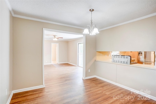 spare room with light wood-type flooring, crown molding, baseboards, a textured ceiling, and a chandelier