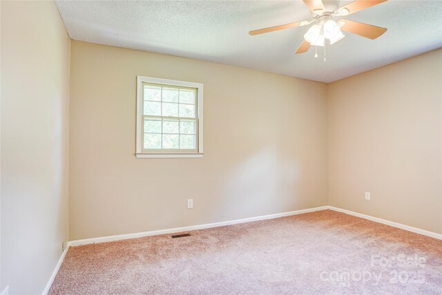 carpeted empty room with baseboards, a ceiling fan, and a textured ceiling