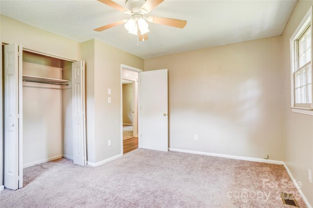 unfurnished bedroom featuring carpet flooring, a closet, baseboards, and ceiling fan