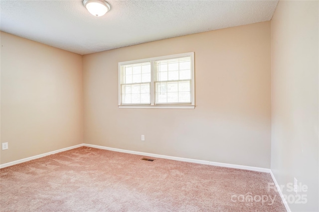 unfurnished room with carpet flooring, baseboards, and a textured ceiling