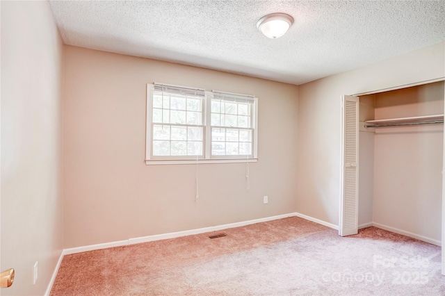 unfurnished bedroom with carpet, a closet, a textured ceiling, and baseboards