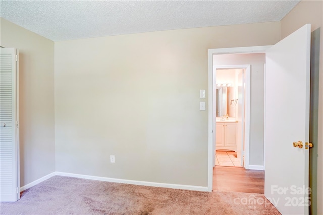 unfurnished bedroom featuring light colored carpet, baseboards, and a sink