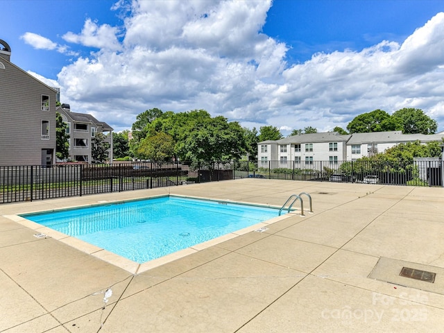 community pool featuring a patio area, fence, and a residential view