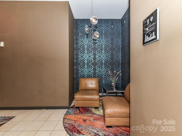 living area with an accent wall, tile patterned floors, and wallpapered walls