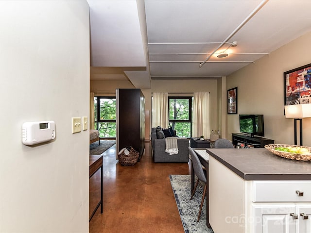 kitchen with concrete flooring, white cabinetry, dark countertops, and healthy amount of natural light